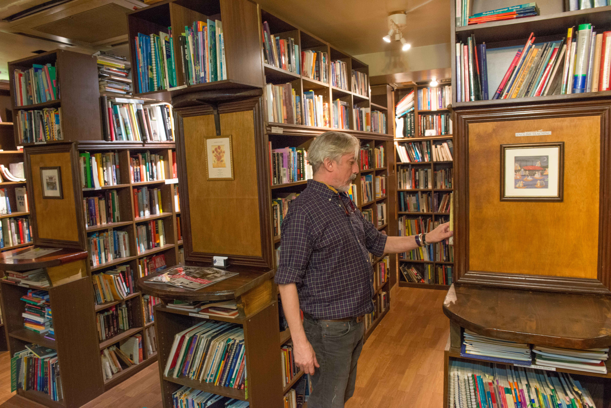 Infinity Books owner Nick Ward looks through stock on his shelves at his bookshop in Tokyo's Sumida Ward. | STEPHEN MANSFIELD